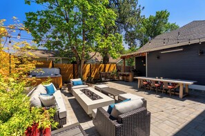 Ein Garten mit Gartenmöbeln, einem Grillplatz und einer überdachten Terrasse.
