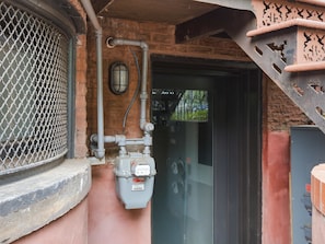 A utility meter mounted on a brick wall, connected to pipes and a window with a metal grill. - Stylish 1BR by Lincoln Park - Capitol Hill (Washington)