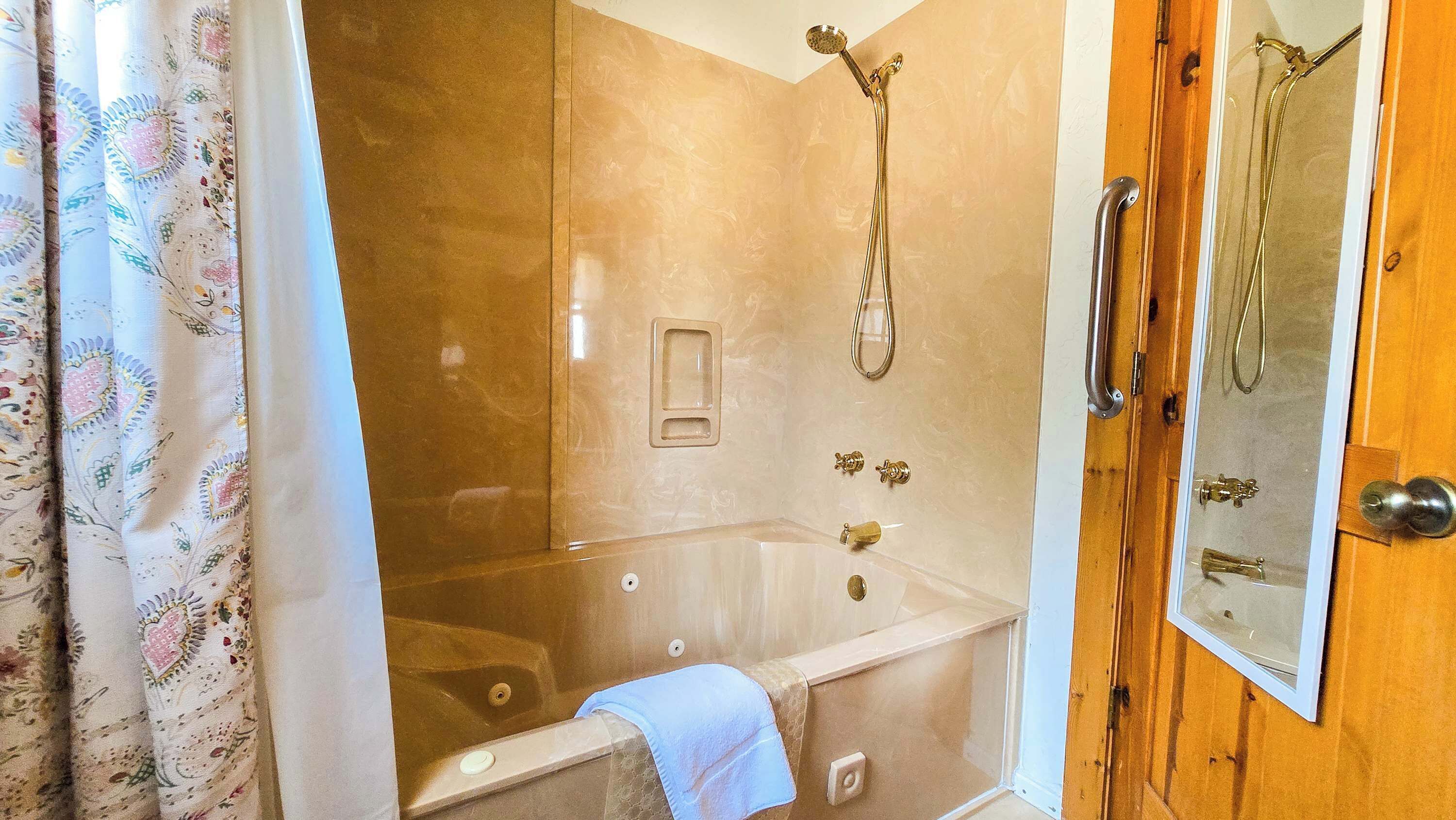 A bathroom with a bathtub, a shower, and a wooden door with a mirror.