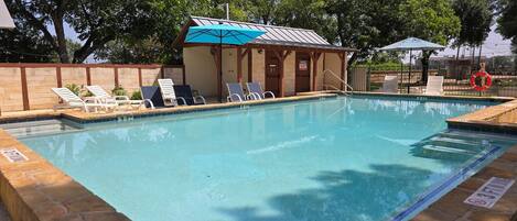 A swimming pool with lounge chairs and a small building with a blue roof.
