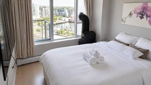 Ein Hotelzimmer mit einem großen Bett, Blick auf die Stadt und einem Gemälde an der Wand.
