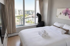 A hotel room with a large bed, a view of the city, and a painting on the wall. - Panoramic False Creek View 2BR/2BA | Pool, Parking (Vancouver)