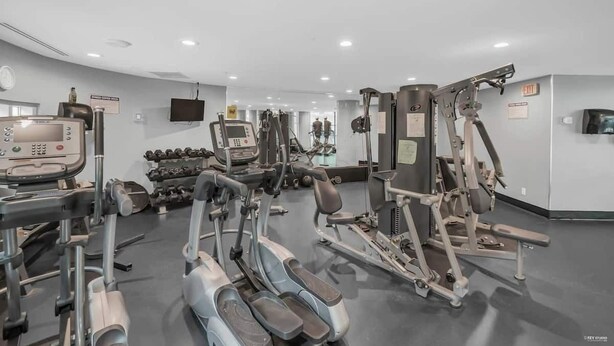 Ein Fitnessstudio mit unterschiedlichen Trainingsgeräten, darunter Laufbänder, Kraftgeräte und Kurzhanteln.