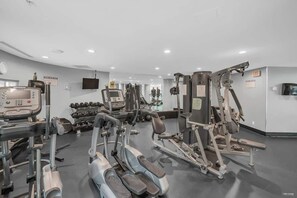 Ein Fitnessstudio mit unterschiedlichen Trainingsgeräten, darunter Laufbänder, Kraftgeräte und Kurzhanteln.