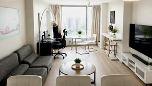 Ein modernes Wohnzimmer mit Sofa, Couchtisch, Fernseher und einem Essbereich mit Tisch und Stühlen.