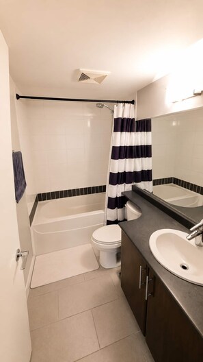 A bathroom with a bathtub, toilet, and sink. - Panoramic False Creek View 2BR/2BA | Pool, Parking (Vancouver)
