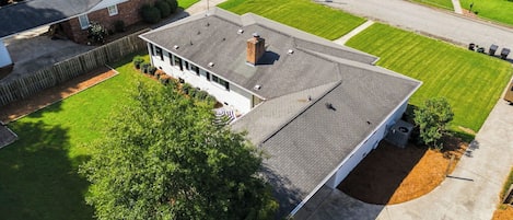 Un barrio residencial con una casa de techo inclinado, un jardín delantero con césped y una entrada para vehículos.