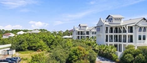 A large, multi-story residential building with a prominent balcony and a well-maintained lawn.