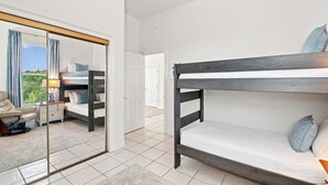 Ein Schlafzimmer mit Etagenbett, Nachttisch, Stuhl und Spiegel.