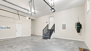 Eine geräumige, gut beleuchtete Garage mit Betonboden, einer Treppe und einer Tür zu einem weiteren Raum.