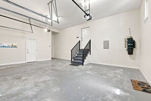 A spacious, well-lit garage with a concrete floor, a staircase, and a door leading to another room. - 5BR 30A Beach House Private Beach Access - Sleeps 10 (Santa Rosa Beach)