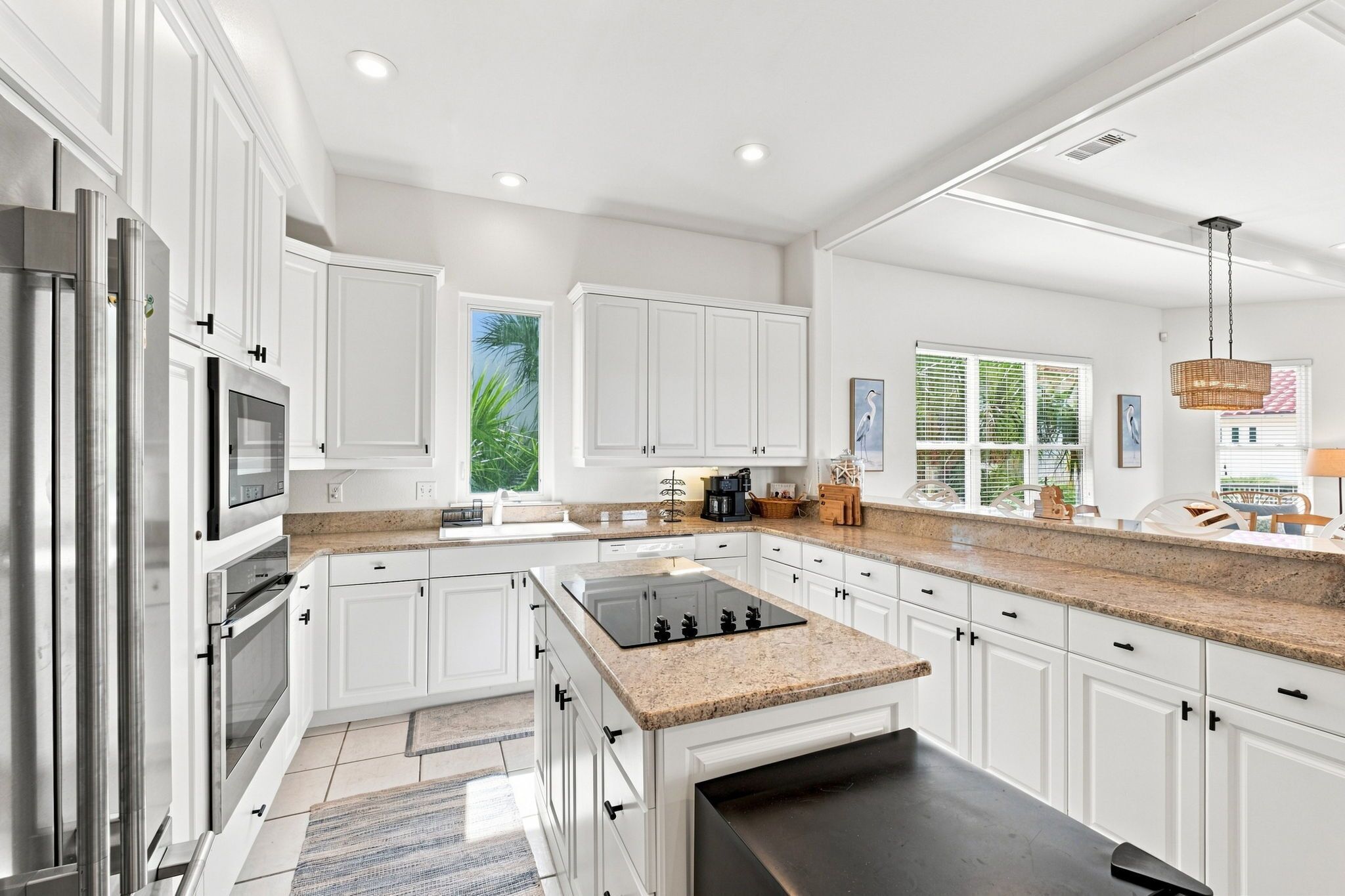 A modern kitchen with white cabinetry, a granite countertop, and a built-in stove.