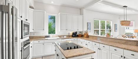 A modern kitchen with white cabinetry, a granite countertop, and a built-in stove.