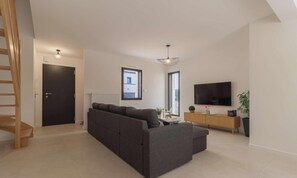 Ein modernes Wohnzimmer mit einer Couch, einem Fernseher und einem Holzkasten.