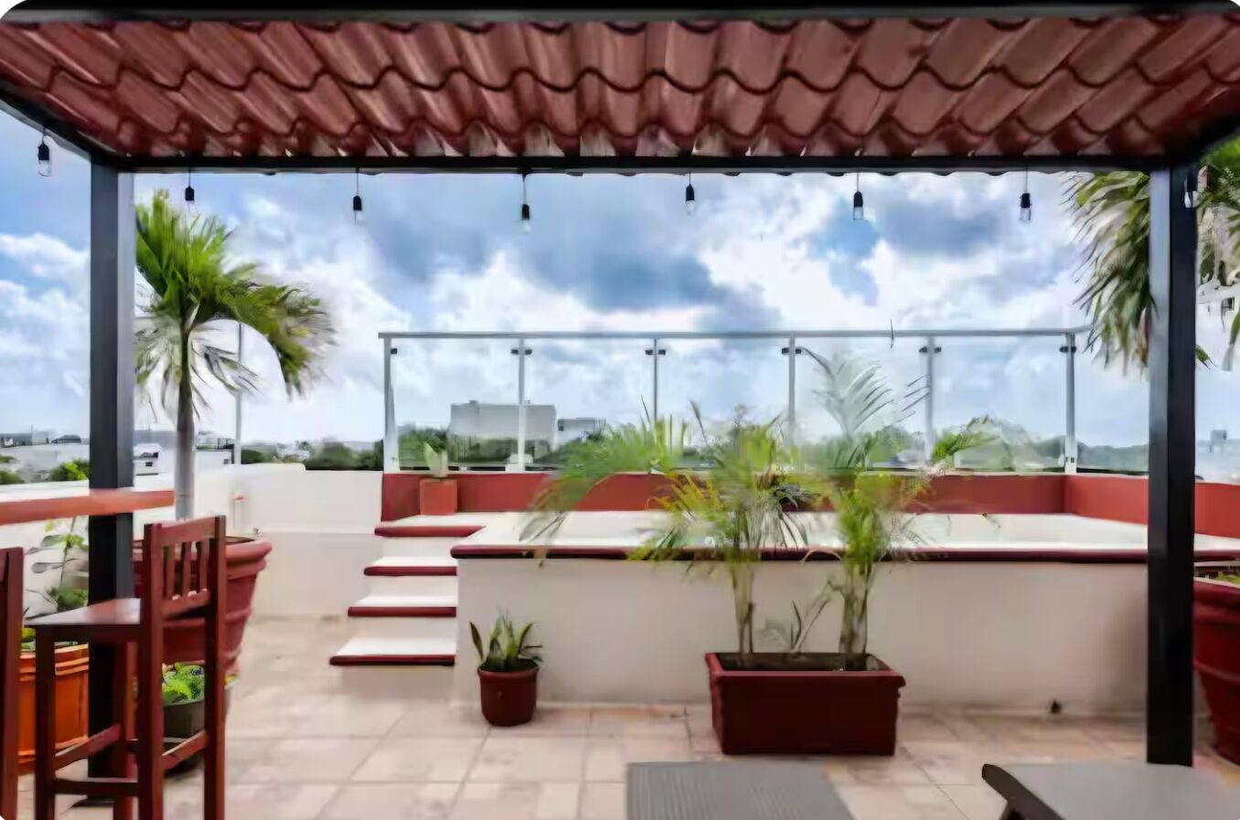 Eine Dachterrasse mit Sitzgelegenheiten im Freien, Blumentöpfen und Blick auf die Stadtlandschaft.