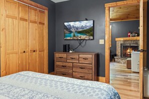 Ein Schlafzimmer mit Bett, Schminktisch, einem Gemälde vom Bergsee und einem Kamin.