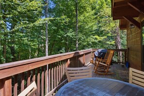 Eine Holzterrasse mit Tisch und Stühlen, umgeben von einem Wald.