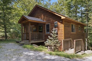 Eine Holzhütte mit Veranda, einer kleinen Terrasse und einem Schild mit der Nummer 132.