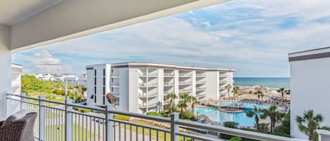 A hotel balcony with a view of a pool and beach.
