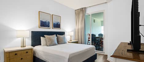 A bedroom with a bed, bedside tables, a ceiling fan, and a view of an outdoor area with chairs.