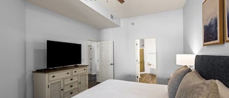 Une chambre d’hôtel équipée d’un lit, d’une télévision, d’un ventilateur de plafond, d’une commode et d’une porte donnant accès à une salle de bain.