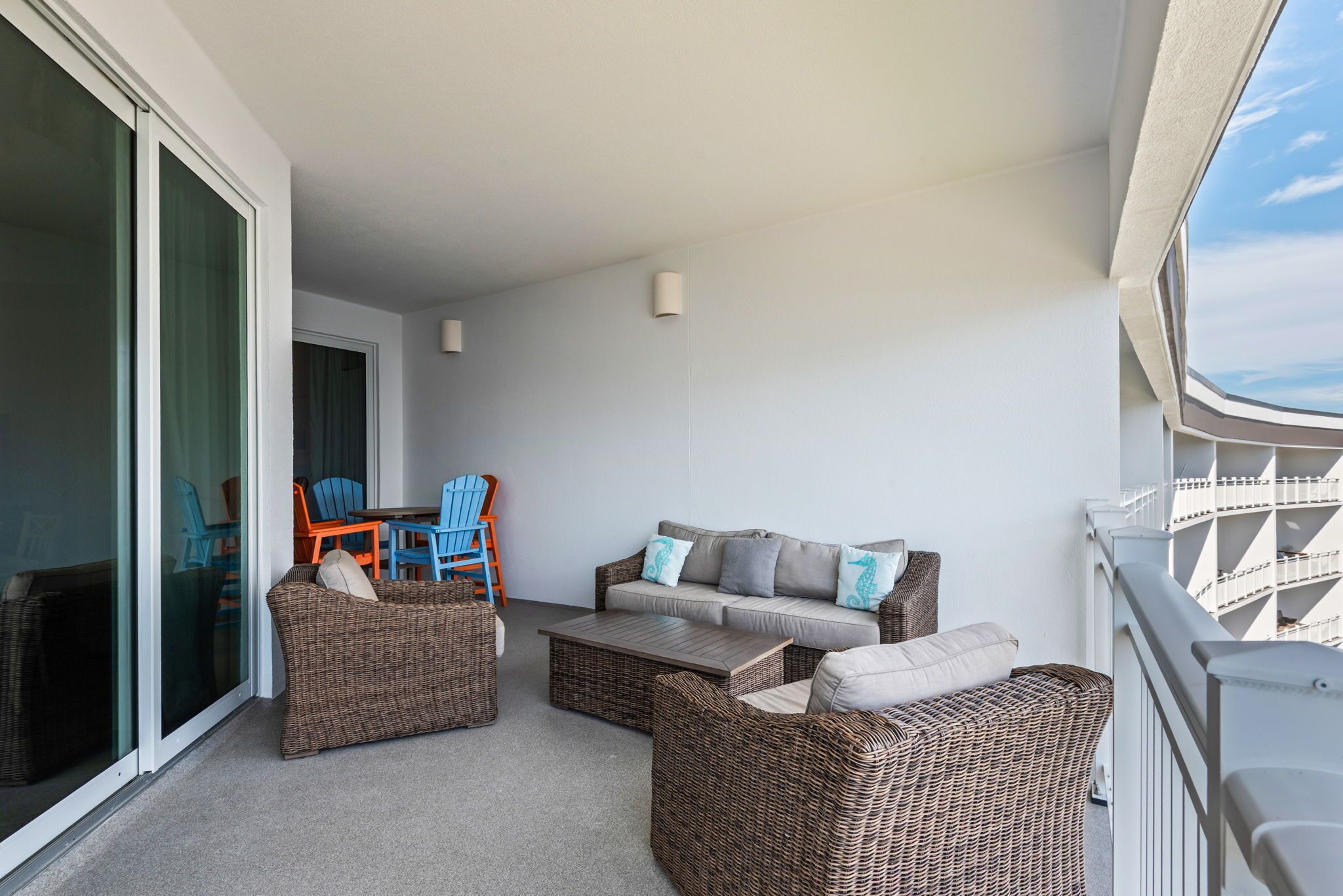 Un balcon agrémenté de meubles en osier, d’un canapé et de fauteuils.