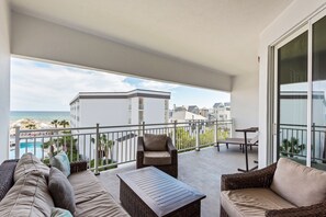 Ein Balkon mit Gartenmöbeln, einem Pool und Blick auf Gebäude und das Meer.