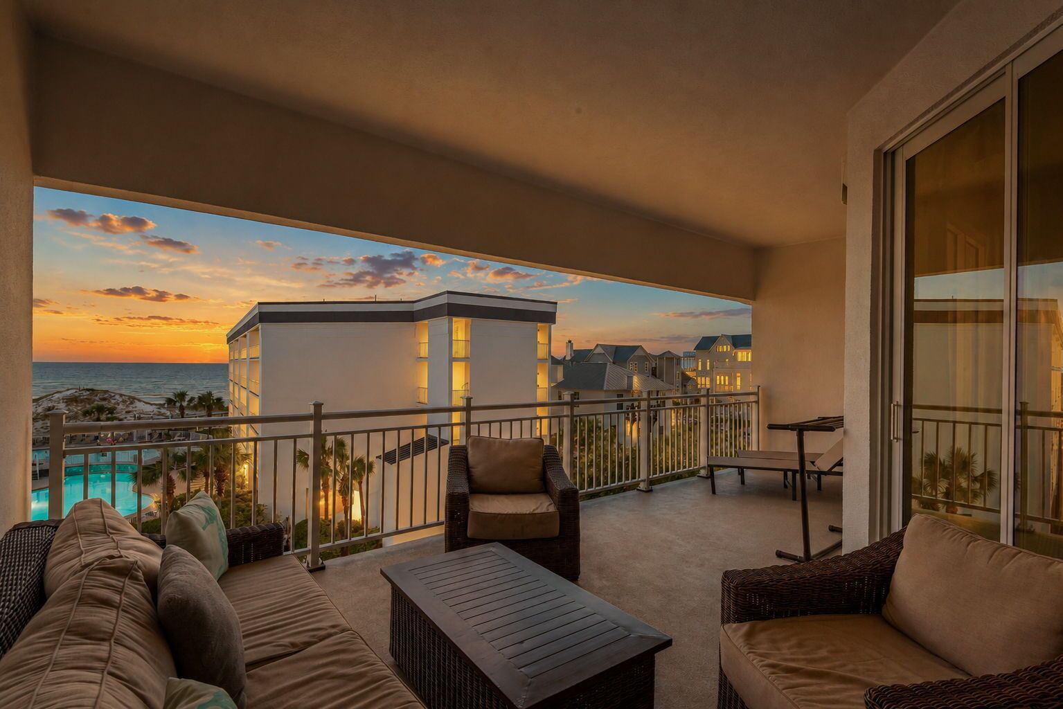A balcony with outdoor furniture, a view of the ocean, and a building in the background.