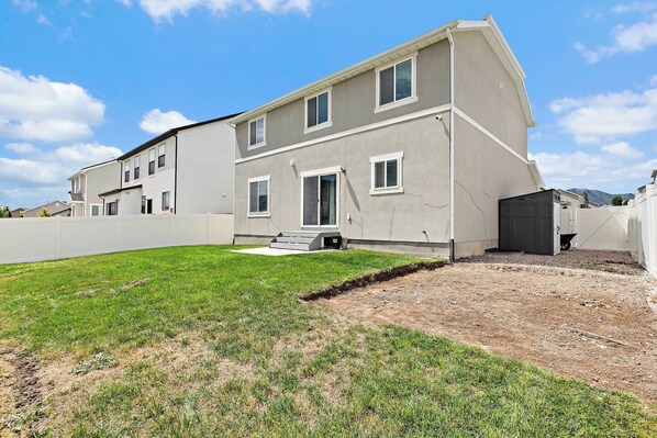 A two-story residential building with a front yard, a garage, and a white fence.