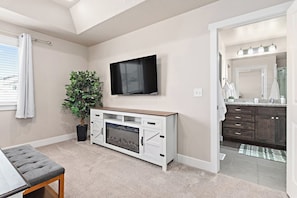 A modern living room with a flat-screen TV, a potted plant, a fireplace, and a view into the adjacent bathroom. - Red Bridge Retreat | Gym | Ping-Pong | Near Golf (Eagle Mountain)