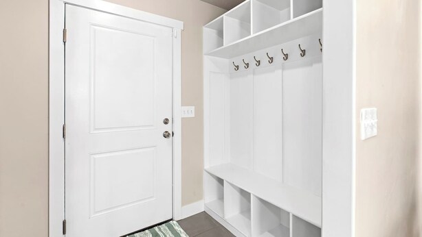 A hallway with a white door, a coat rack with hooks, and a patterned doormat. - Red Bridge Retreat | Gym | Ping-Pong | Near Golf (Eagle Mountain)