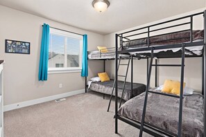A room with bunk beds, a window with blinds, a picture on the wall, and a ceiling light. - Red Bridge Retreat | Gym | Ping-Pong | Near Golf (Eagle Mountain)