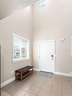 A hallway with a bench, a door, and a window with blinds. - Red Bridge Retreat | Gym | Ping-Pong | Hot Tub (Eagle Mountain)