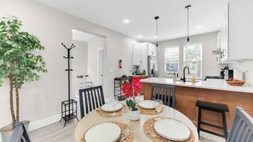 A modern kitchen with white cabinets, a central island, and a dining area set for four.