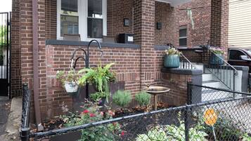 A brick house with a front porch, a small garden, and a mailbox.
