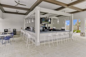 A modern bar area with white bar stools, a counter, and ceiling fans. - Stay in Style! 6BR Storey Lake Retreat with Pool & Spa (Kissimmee)