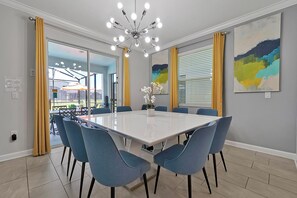 Une salle à manger moderne avec une grande table rectangulaire, des chaises bleues et un lustre.