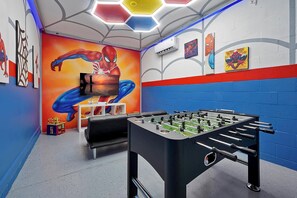 A room with a foosball table, a mural of Spider-Man, and a wall with various artworks. - Stay in Style! 6BR Storey Lake Retreat with Pool & Spa (Kissimmee)