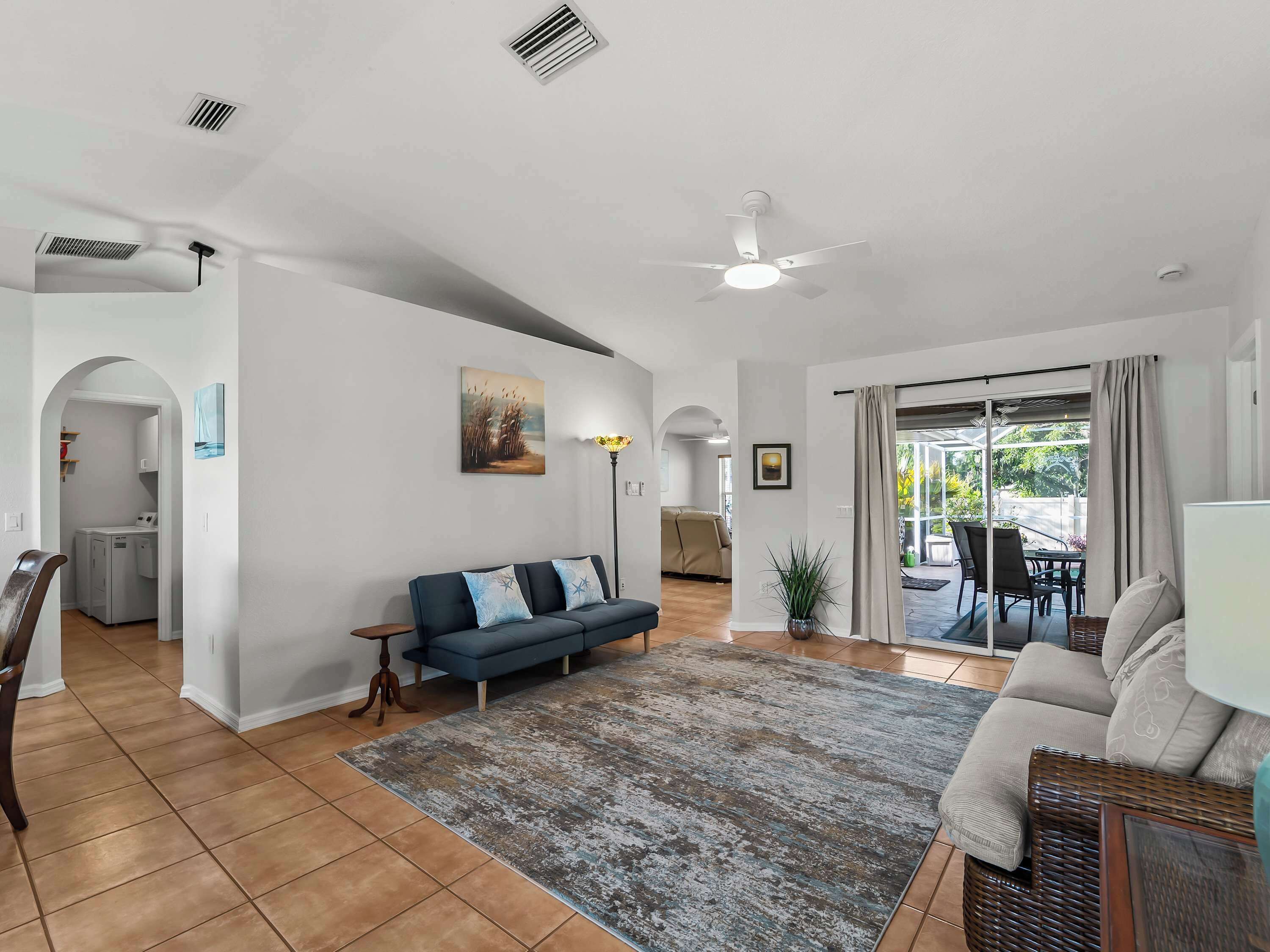 Un vaste espace de vie comprenant un canapé, une table à manger et un ventilateur de plafond.