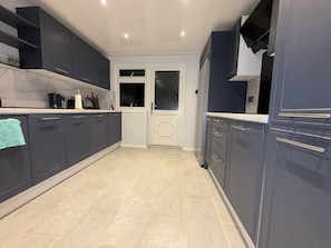 Una cocina moderna con gabinetes oscuros, una encimera blanca y piso de baldosas.