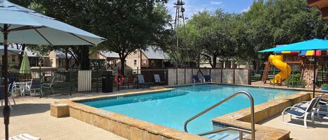 A swimming pool with a lifeguard stand, lounge chairs, and a windmill in the background.