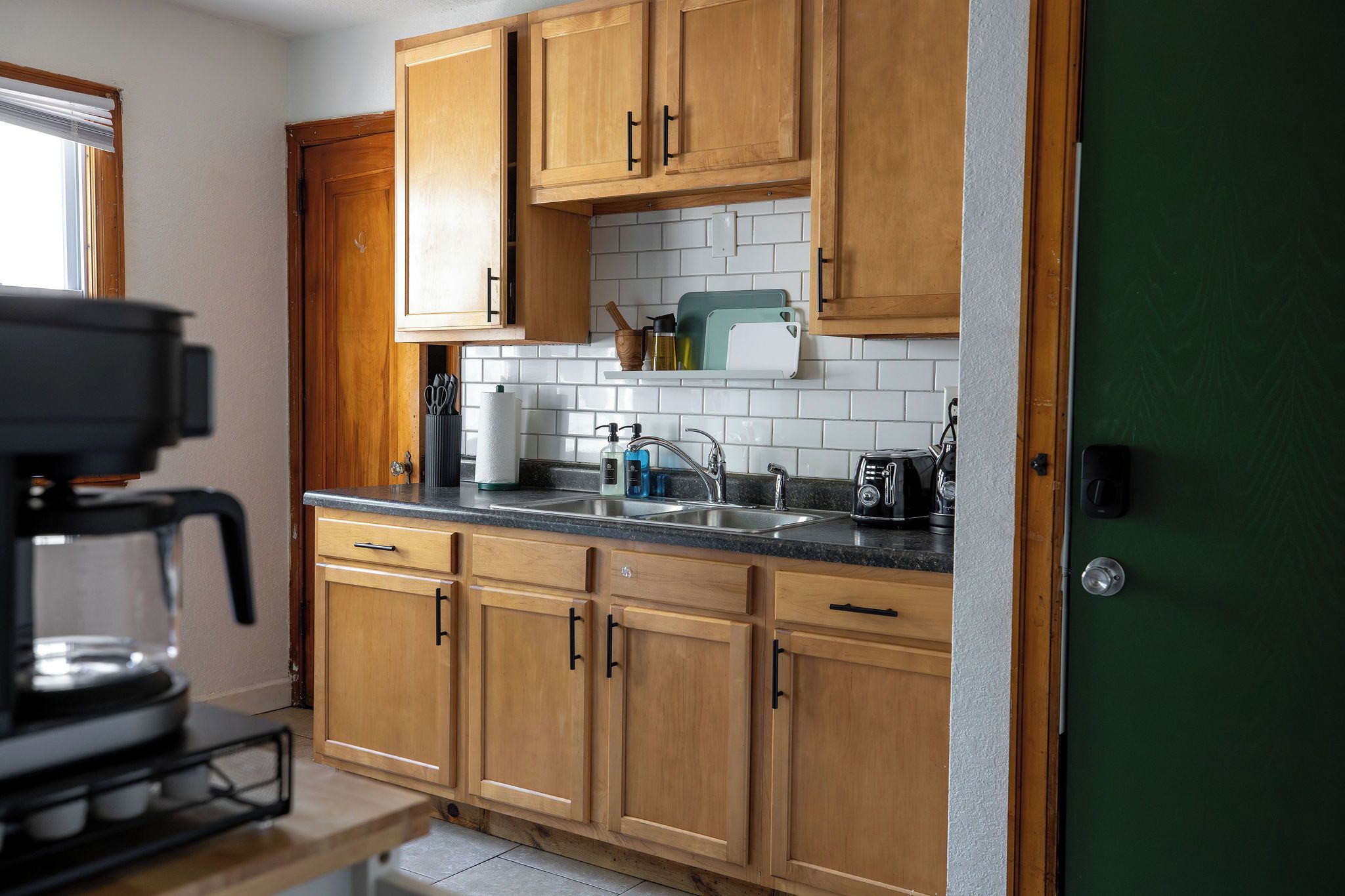 A kitchen with wooden cabinets, a countertop, a sink, and a coffee machine.