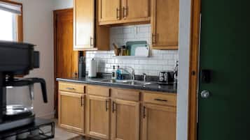 A kitchen with wooden cabinets, a countertop, a sink, and a coffee machine.