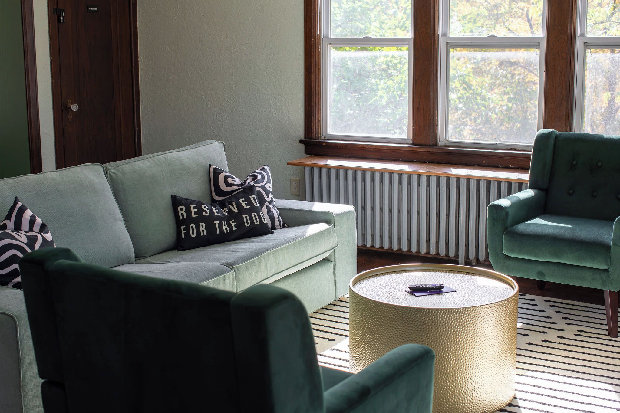 A room with a green sofa, a green armchair, and a round coffee table.