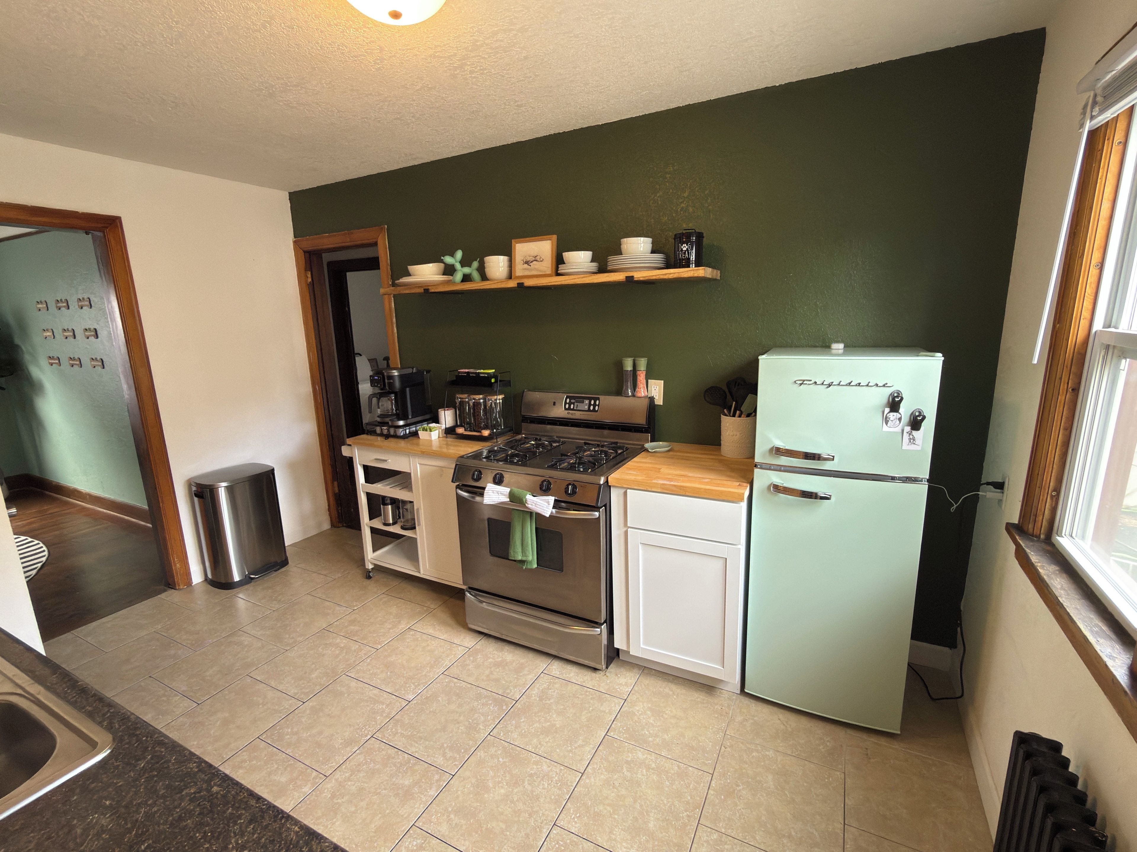 A compact kitchen with a gas stove, oven, and a vintage-style refrigerator.