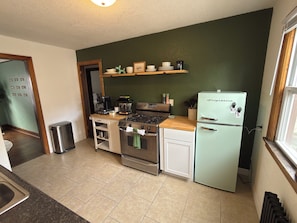 A compact kitchen with a gas stove, oven, and a vintage-style refrigerator. - Paws on Lowry: Mint Sleek Retro • Pet-Friendly (Minneapolis)
