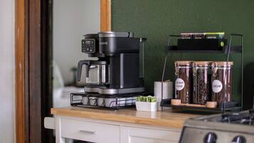 Une petite cuisine équipée d’une machine à café, de pots de thé et d’un récipient contenant des friandises pour chiens.