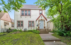 A two-story house with a front porch, a stone foundation, and a red roof. - Paws on Lowry: Mint Sleek Retro • Pet-Friendly (Minneapolis)