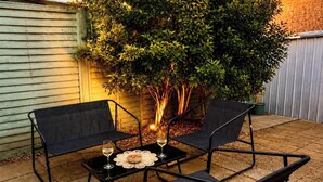An outdoor patio with a table and chairs, a small fire, and a tree. - Stylish 2-Bed Bedford Home | Sleeps 4 + Sofa Bed | Free Parking |Super Fast WiFi (Bedford)