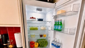A kitchen with a microwave above the refrigerator, which is stocked with various food items and beverages. - Stylish 2-Bed Bedford Home | Sleeps 4 + Sofa Bed | Free Parking |Super Fast WiFi (Bedford)